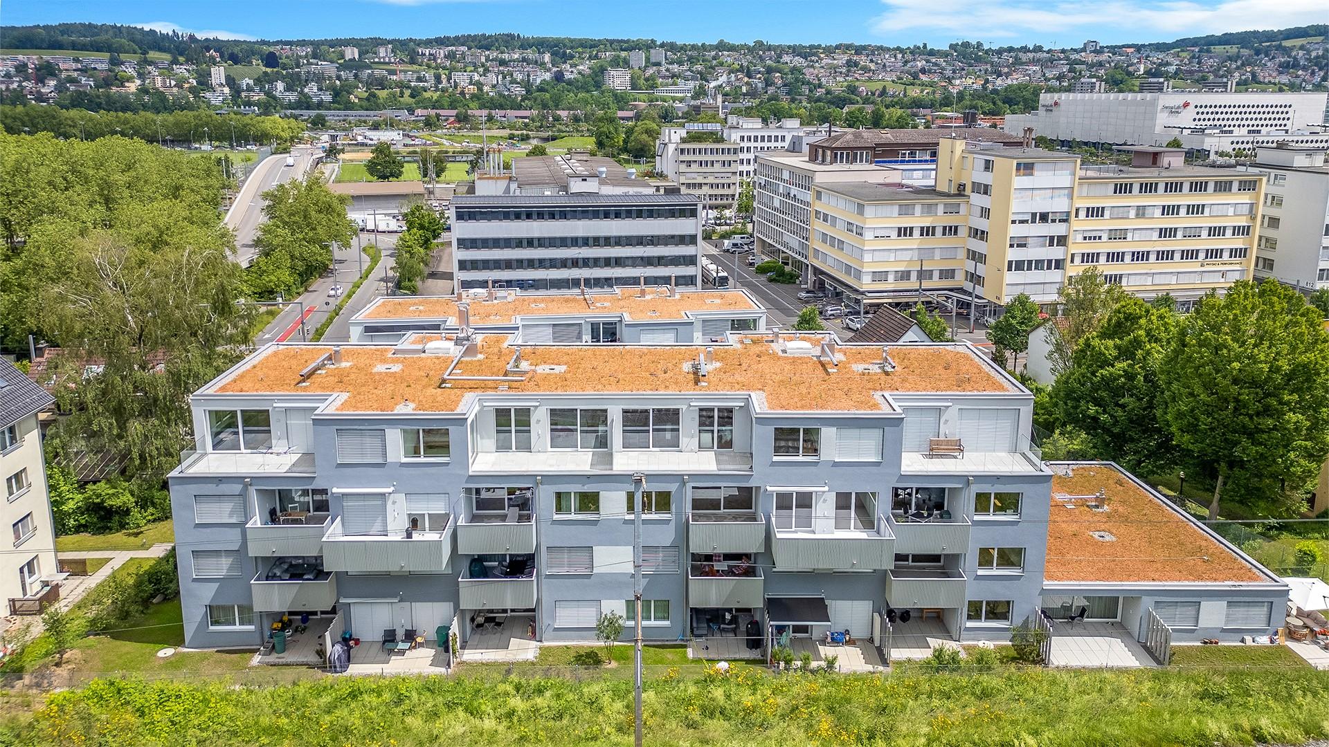 Luftaufnahme eines Mehrfamilienhauses mit begrüntem Umfeld